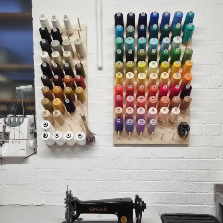 Sewing machine with thread spools on a white brick wall