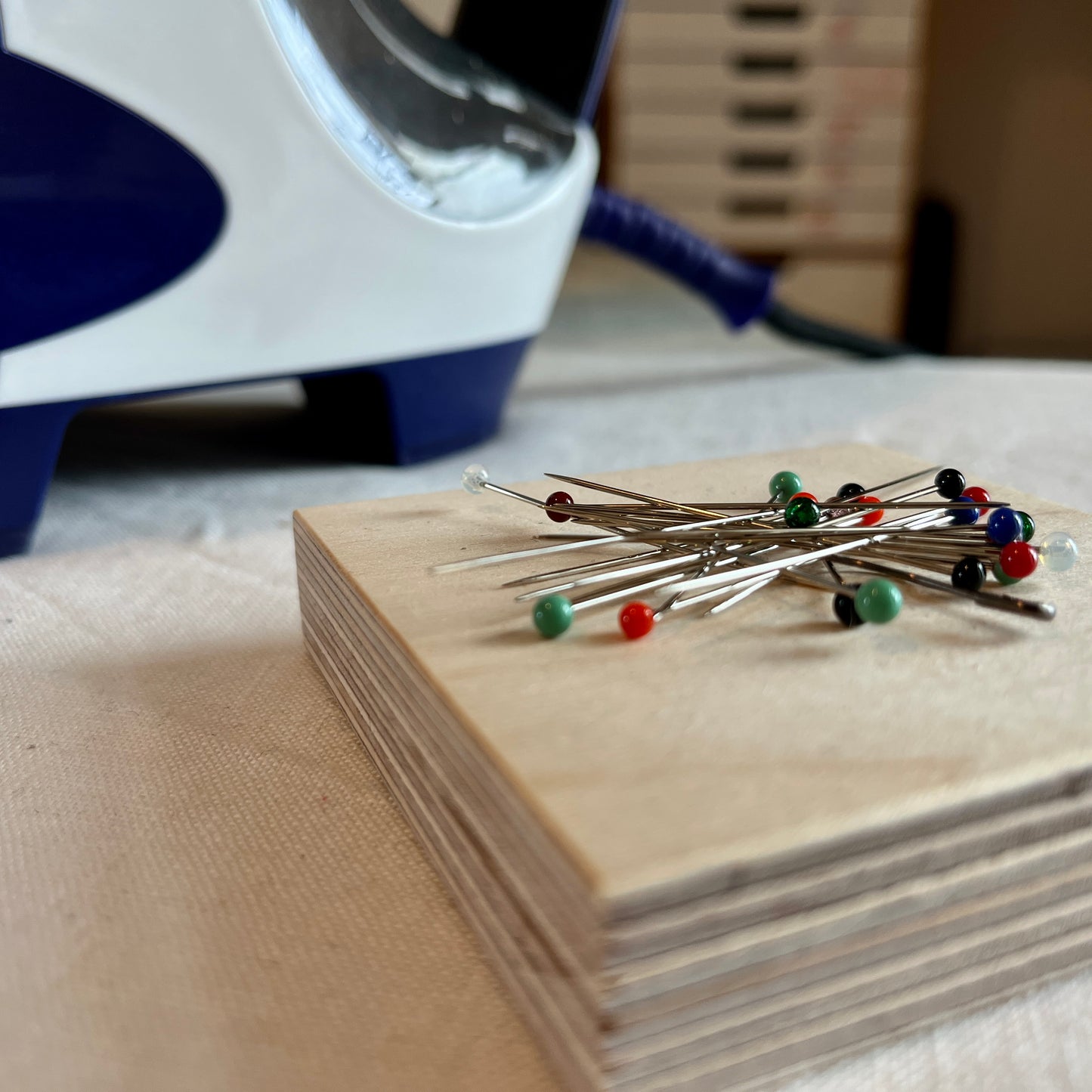 Pins on a magnetic wooden pin holder next to an iron