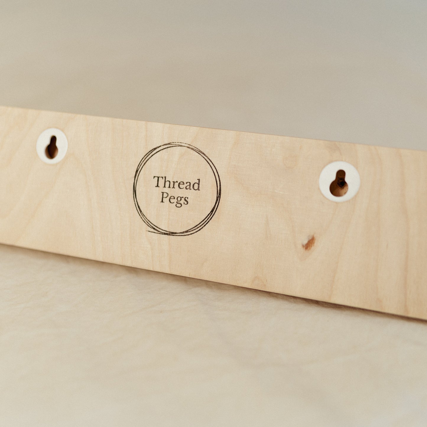 Wooden peg board with 'Thread Pegs' label on a beige background