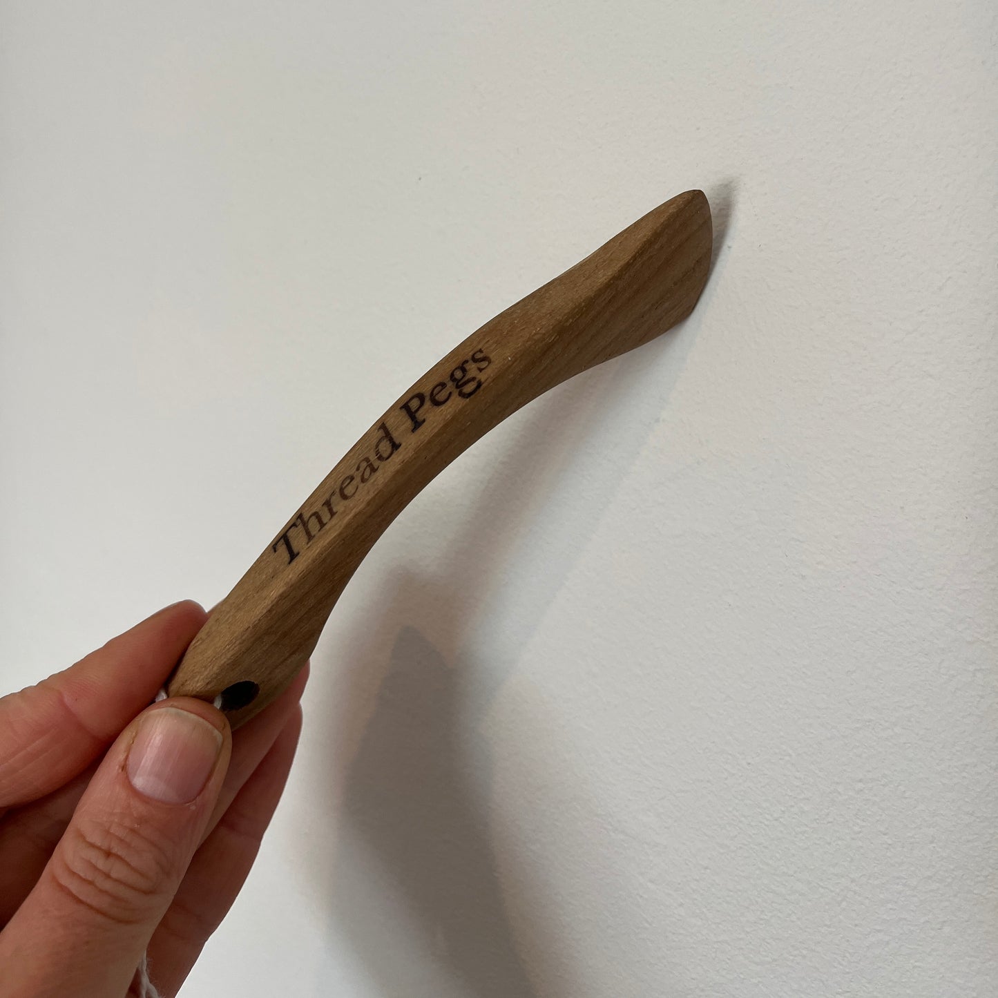 Wooden Hera Marker held by a hand on a white background