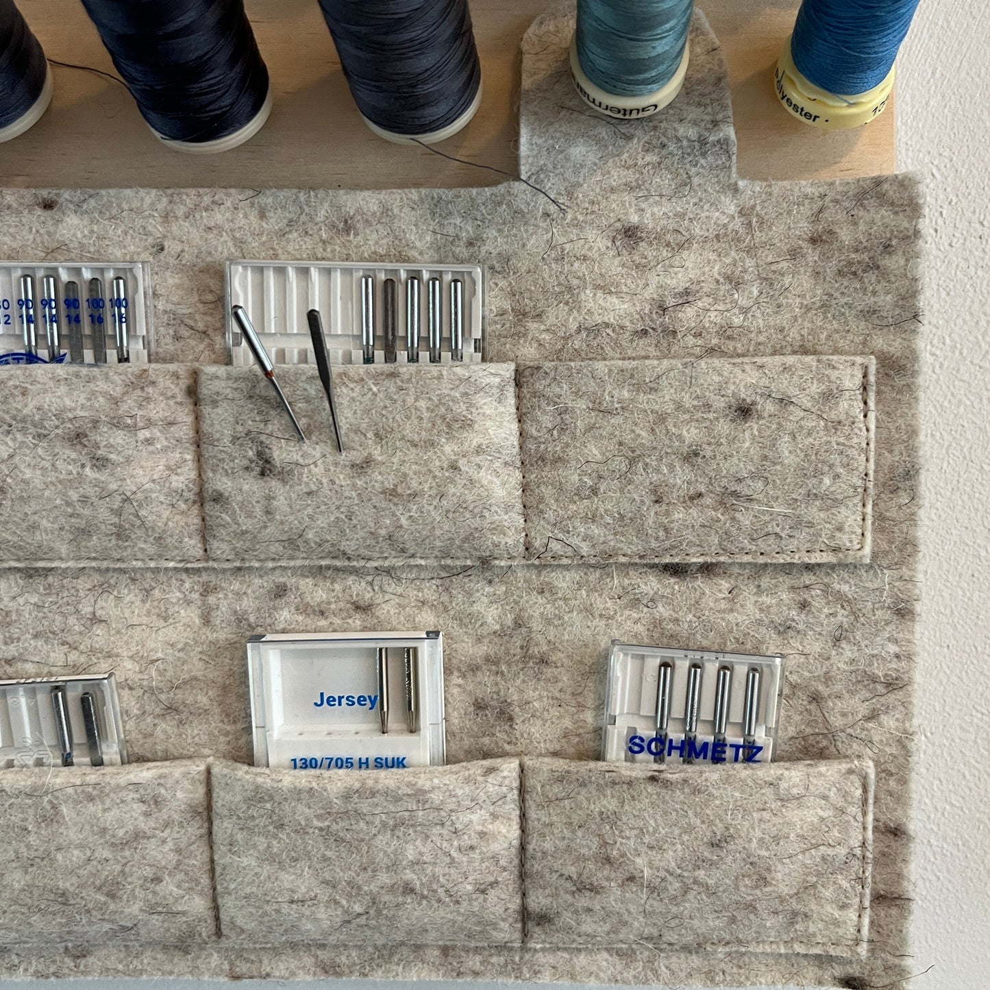 Spools of thread and felt pouch for needle storage on a textured surface