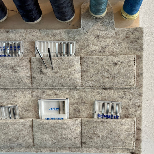 Spools of thread and felt pouch for needle storage on a textured surface