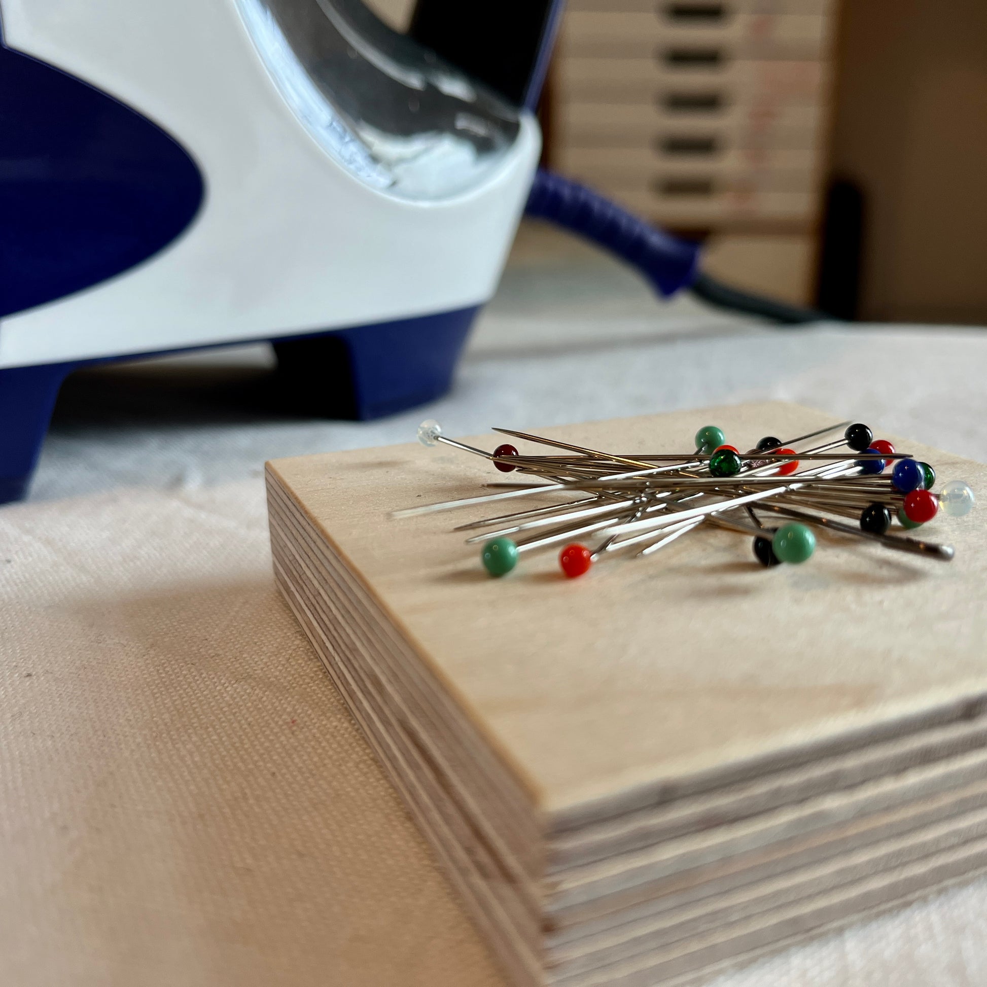 Pins on a magnetic wooden pin holder next to an iron