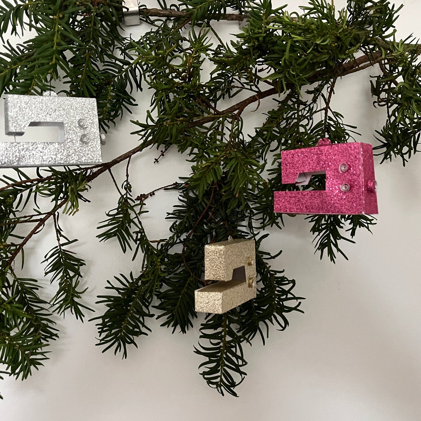 Three mini sewing machines hanging on a christmas tree