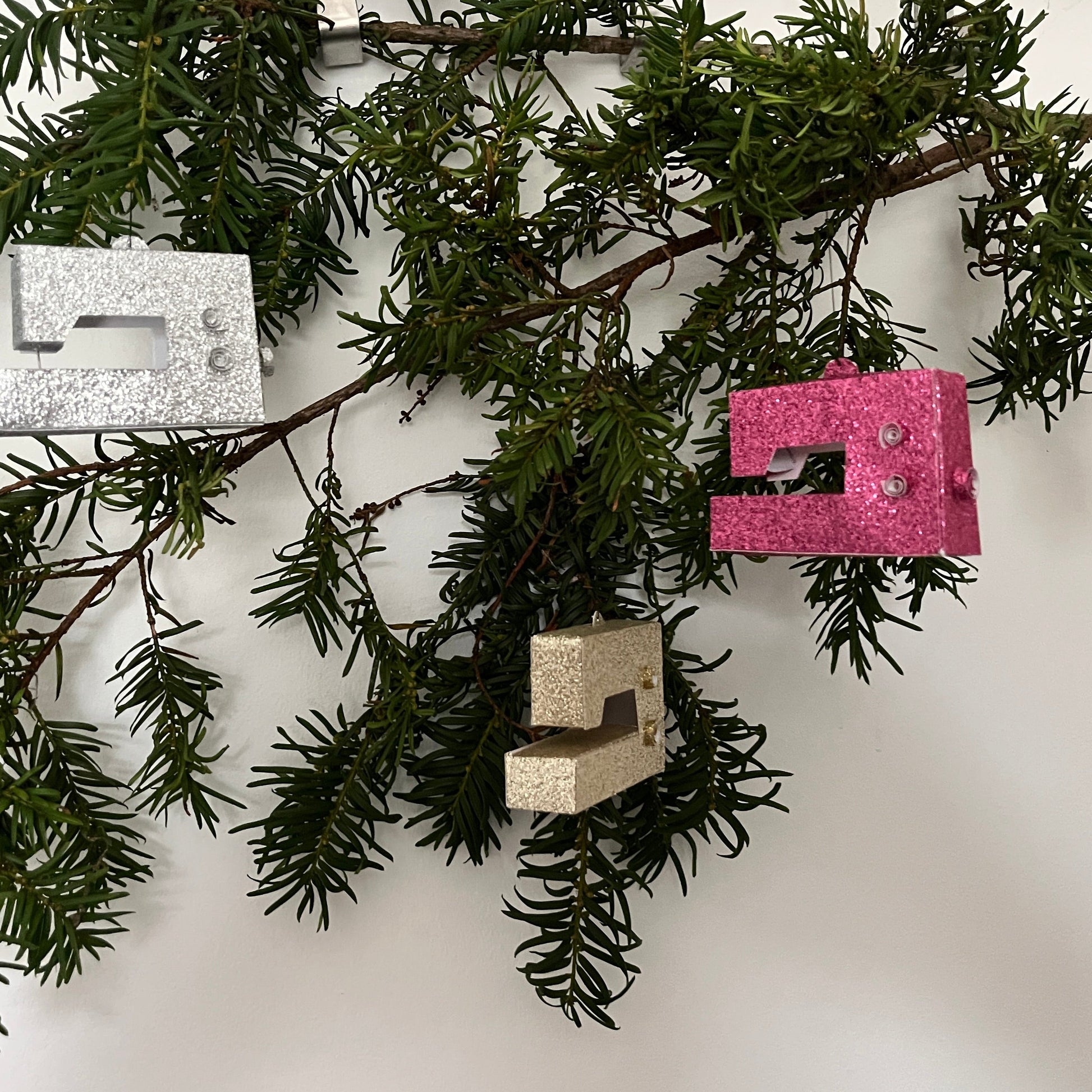 Three mini sewing machines hanging on a christmas tree