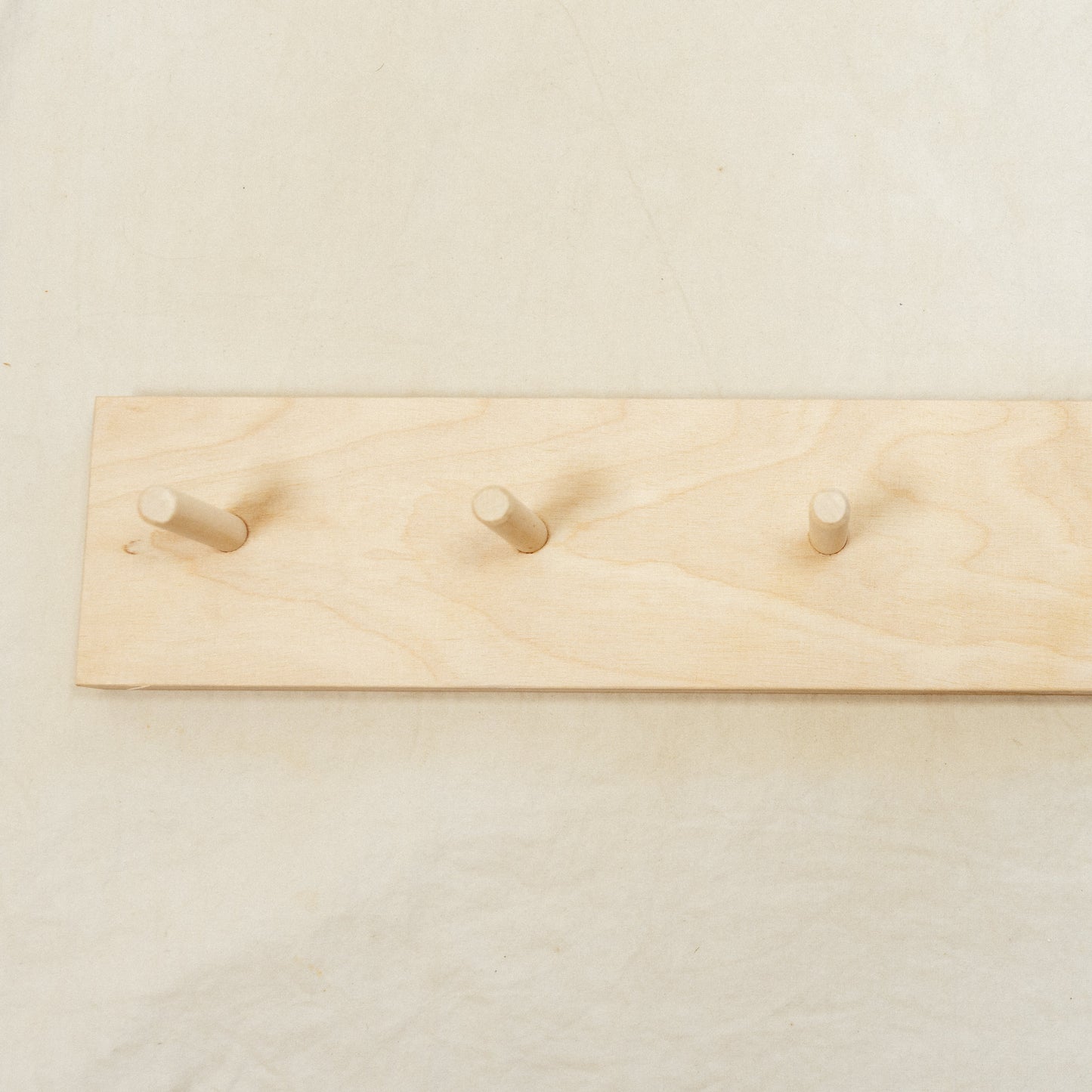 Wooden rack with five hooks on a plain background