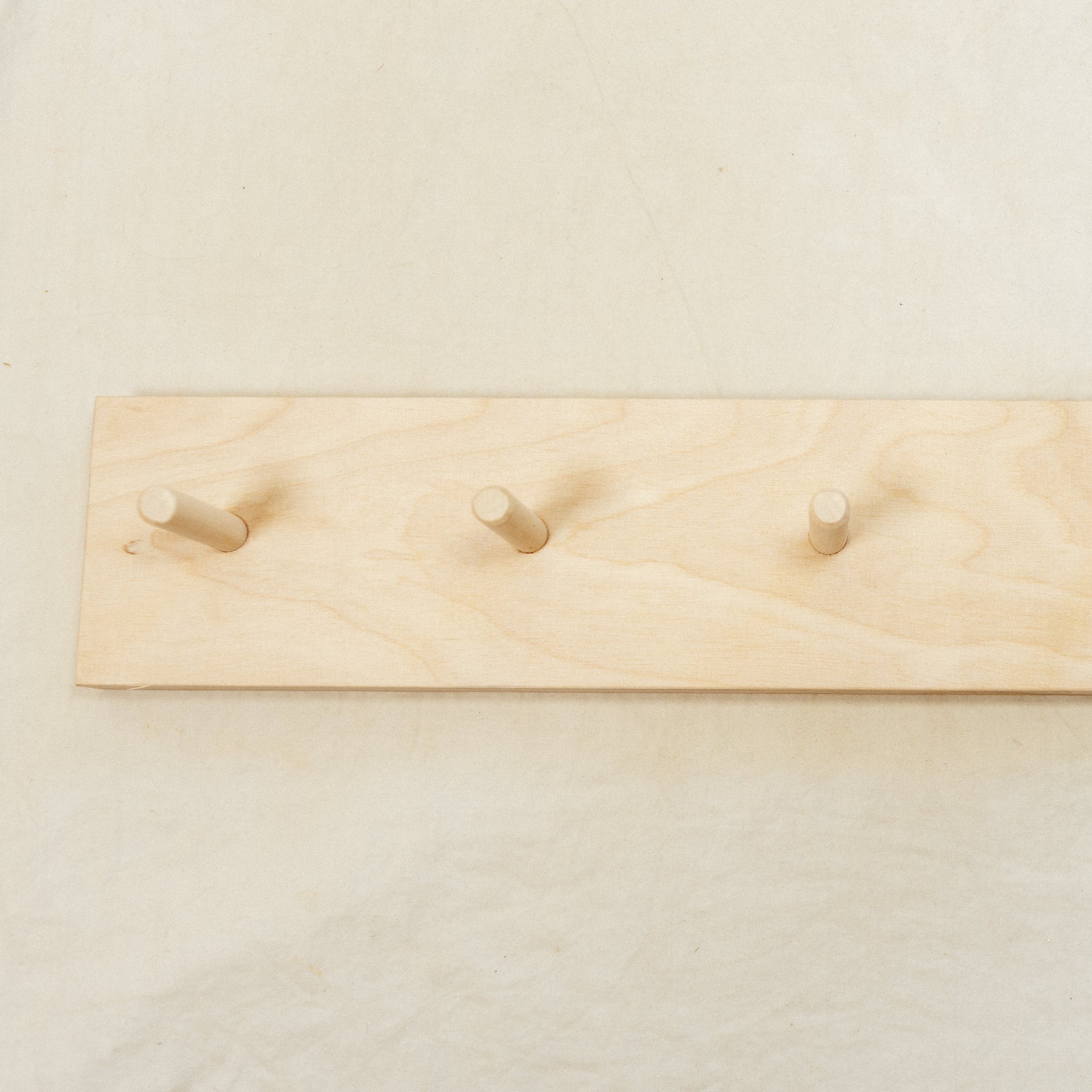 Wooden rack with five hooks on a plain background